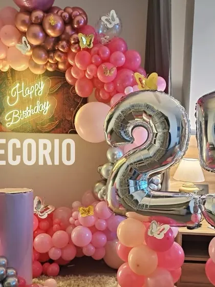 A fun and festive 25th birthday setup with a pink, rose gold, and silver color scheme. The decor includes large foil '25' balloons and a lit 'Q' marquee letter.