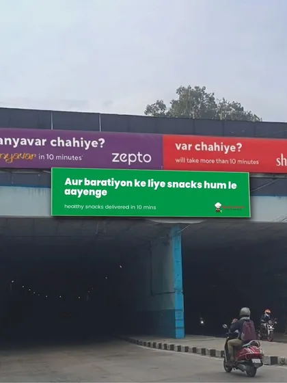Aur baratiyon ke liye snacks hum le aayenge. This fun billboard shows our partnership with Zepto, promising healthy snacks delivered in just 10 minutes.