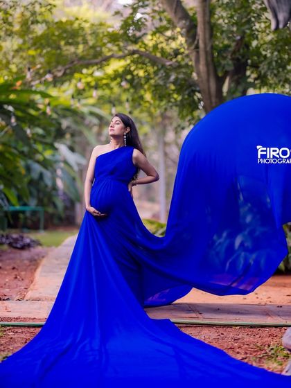 A stunning maternity portrait with a flowing blue gown set against a pathway in our lush garden, creating a powerful and elegant image.