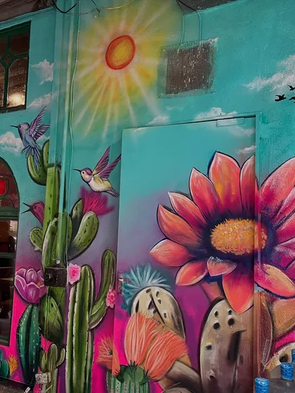 A corner of the Mexican mural, featuring a giant painted flower next to the cacti and sun.