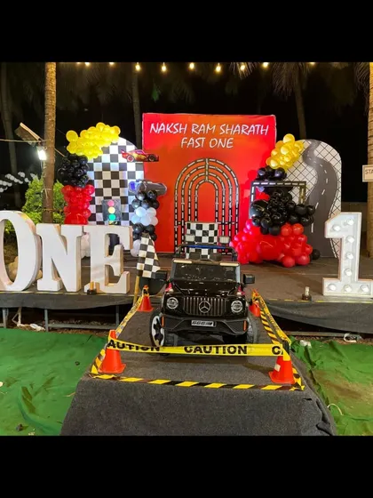 Ready, set, go. For this "Fast One" first birthday, we created a complete race car theme with a track, checkered flag balloons, and even a mini Mercedes for the birthday boy to make a grand entrance.