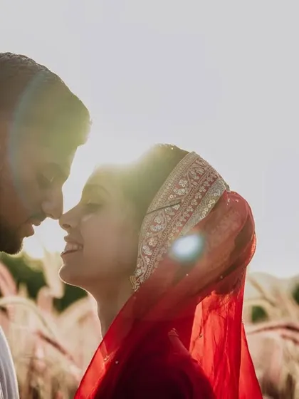 A sun-flared, intimate close-up of a couple, capturing the warmth and love between them in a field in Rajasthan.