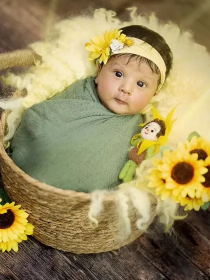 Hello, sunshine. This newborn looks so sweet and bright in a basket adorned with cheerful sunflowers.