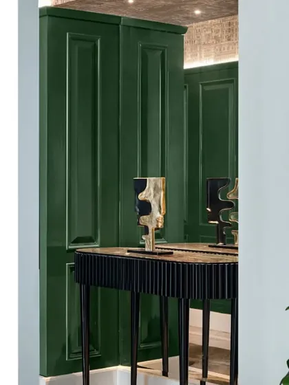 A detail shot of the console table in the grand green foyer. The deep green lacquered panels and custom art pieces create a sophisticated and welcoming vignette.