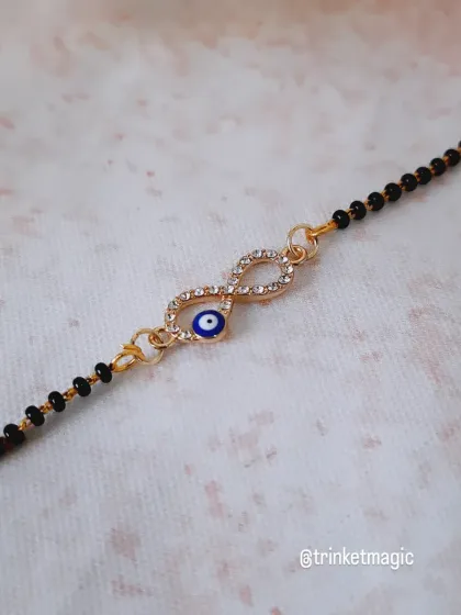 Infinite protection. This mangalsutra bracelet features an infinity symbol intertwined with an evil eye, symbolizing everlasting love and protection for your sibling.