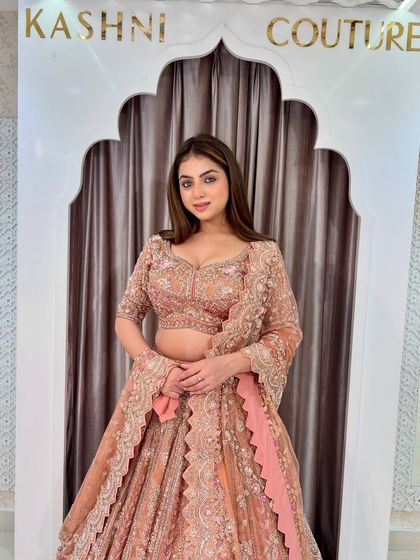 A closer look at the peach-rust lehenga, focusing on the detailed work on the blouse and the scalloped edges of the sleeves.