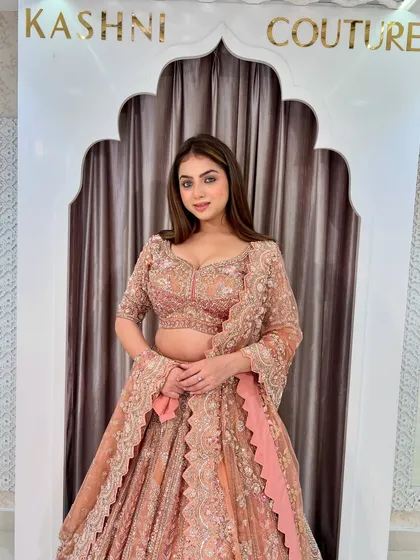 A closer look at the peach-rust lehenga, focusing on the detailed work on the blouse and the scalloped edges of the sleeves.