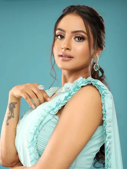 A side profile showing the elegant ponytail hairstyle and the delicate details of her saree.