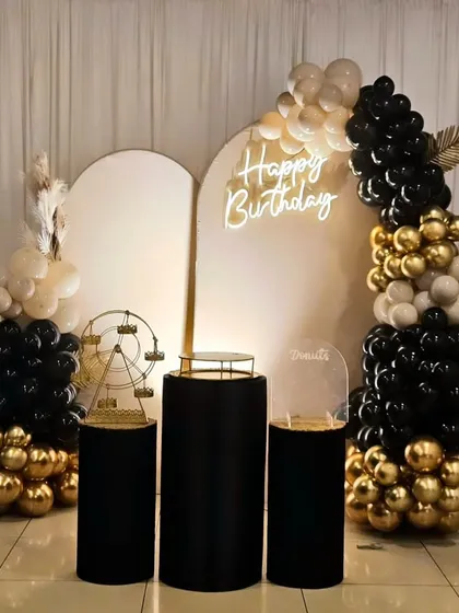 A sophisticated black, white, and gold theme for a birthday. This setup includes an organic balloon garland, dual arched backdrops, and props like a miniature Ferris wheel.