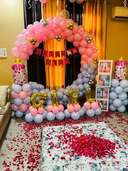 Celebrating a baby girl with this full decoration set. It includes a circular balloon arch in pink and grey, 'GIRL' foil letters, and transparent 'BABY' boxes, all arranged for a perfect welcome home photo.