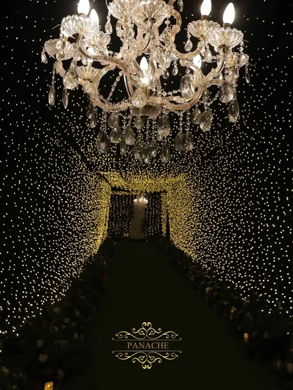 We transform spaces into magical realms. This tunnel of countless fairy lights, leading to a grand chandelier, creates an enchanting entrance for a glamorous cocktail night, promising an evening of wonder.