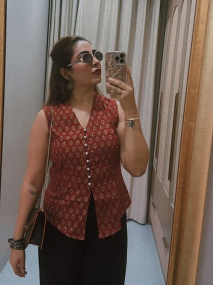 A close-up on the details of this fusion look. The printed waistcoat, stacked bangles, and retro sunglasses add personality and a contemporary twist to the outfit.