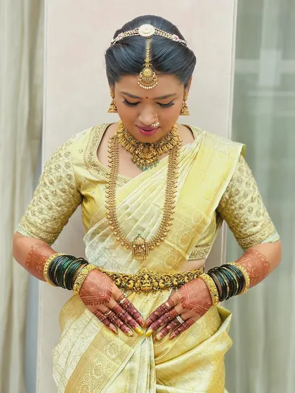 A bride in a light gold Kanchipuram saree. Her custom blouse features a delicate, all-over embroidered pattern, creating a look of subtle and sophisticated elegance.