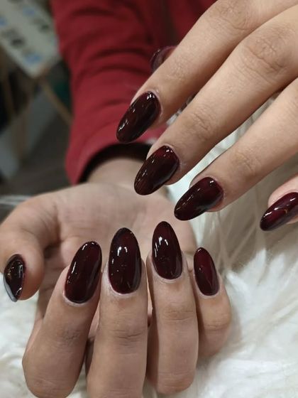A beautiful set of almond-shaped nails in a deep, glossy oxblood red.