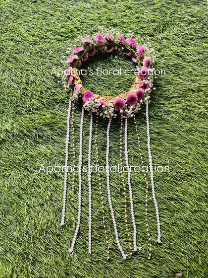 A fresh floral hair tiara designed for a Haldi bride. This piece features purple flowers and baby's breath with long, delicate pearl tassels that cascade down the hair.