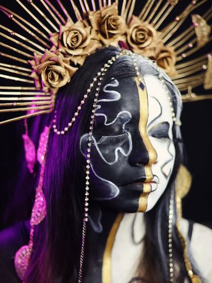 A high-concept, black-and-white split-face look with gold accents and a dramatic headpiece.
