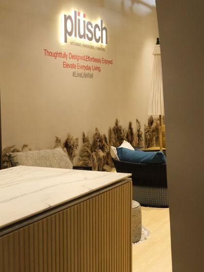 A glimpse into the booth's interior, where the brand's tagline is displayed. The design uses natural elements like pampas grass to soften the space and complement the luxurious furniture on display.