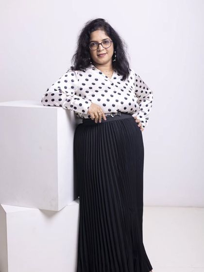 A full-length view of this chic and modern professional look. The belted waist on the pleated skirt creates a defined silhouette, while the classic print of the blouse keeps it timeless. This is a versatile outfit that works for meetings, presentations, and networking events.