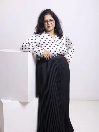A full-length view of this chic and modern professional look. The belted waist on the pleated skirt creates a defined silhouette, while the classic print of the blouse keeps it timeless. This is a versatile outfit that works for meetings, presentations, and networking events.