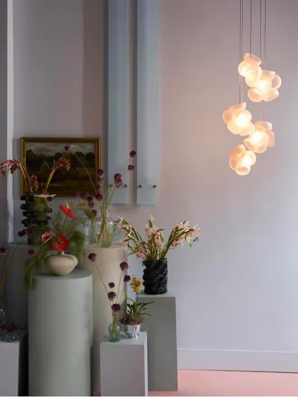 A small, vertical cluster of Bocci 100 pendants provides ambient light in a stylish room, complementing the artistic decor.