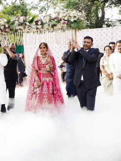 The bride makes her entrance, walking on a cloud of low-lying smoke under a beautiful floral 'phoolon ki chadar'. Professional dancers in traditional attire lead her procession, adding grace and elegance to this special moment.