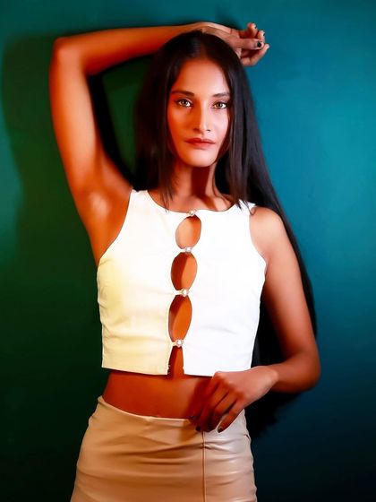 A strong and confident pose against a teal background. The lighting is dramatic, and her expression is powerful.