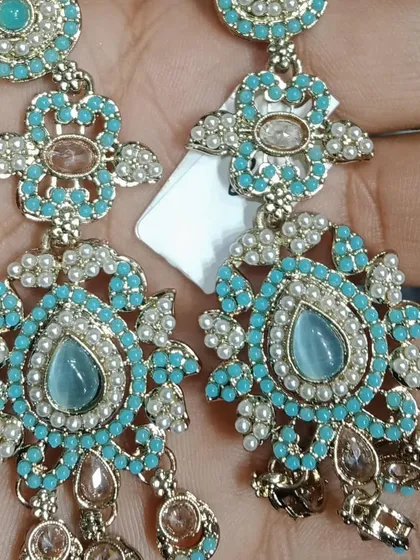 A pair of turquoise-colored earrings with intricate beadwork and polki details.
