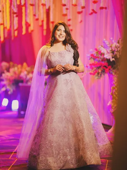 A full-length view of the light purple gown with an attached sheer cape. This rental offers a modern and ethereal look, ideal for a bridesmaid or a wedding guest.
