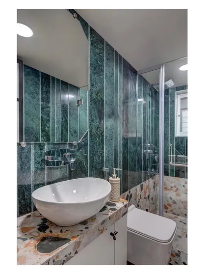 We celebrate the inherent beauty of natural materials. This bathroom in a Mumbai home features bold green marble and terrazzo, creating a rich, textured space that feels both luxurious and grounded, proving that utility areas can be statements of personal style.
