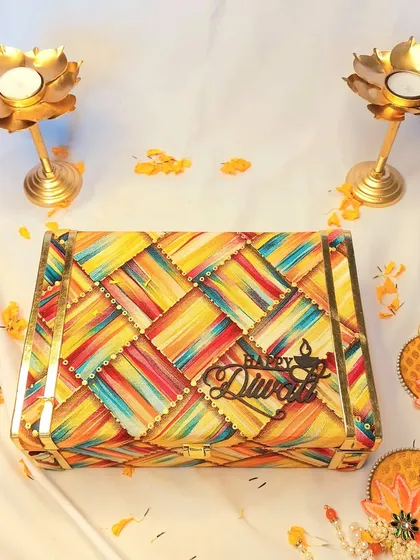 This vibrant, multi-colored Diwali box is designed to be as joyful as the festival itself. Inside, I've included a set of copper glasses, potlis of nuts, shubh labh hangings, and a wooden diya.