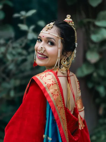 A radiant Maharashtrian bride in her stunning red and blue Nauwari saree. This portrait captures her grace, happiness, and the intricate details of her traditional bridal look.