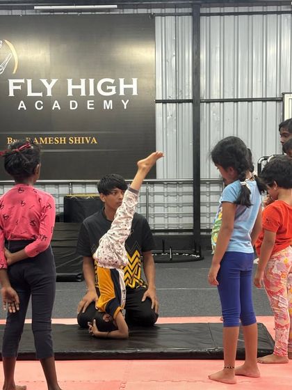 I demonstrate the correct headstand form while the kids' class observes, learning through watching and doing.