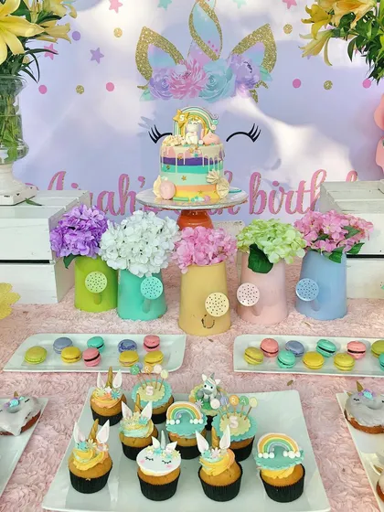 The dessert table for a unicorn-themed party, complete with a rainbow drip cake, unicorn-topped cupcakes, and pastel macarons. Every treat was designed to be part of the magical experience.