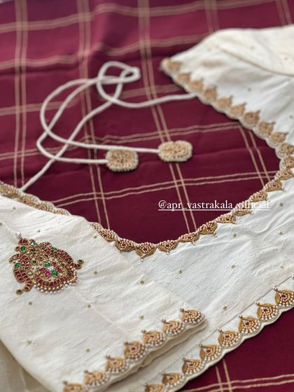 The back of the off-white blouse, showing the tie-up detail and a single motif.