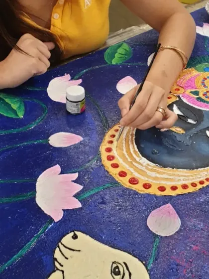 A close-up shot of a student adding delicate details to a large Pichwai painting, showing the focus and devotion that goes into such a piece.