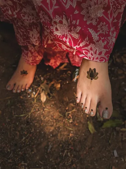 A very minimalist and modern take on foot mehendi. This design features a single, bold lotus flower on each foot, perfect for someone who wants a symbolic and chic tattoo-like design.