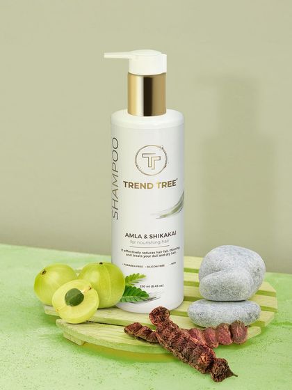 A styled shot of Trend Tree shampoo with its key ingredients, amla and shikakai. This educational approach visually informs customers about the product's formulation.