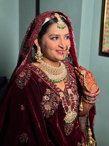 The bridal glow is real. This bride shines in a deep maroon velvet lehenga, with makeup that highlights her features and complements the richness of the fabric.