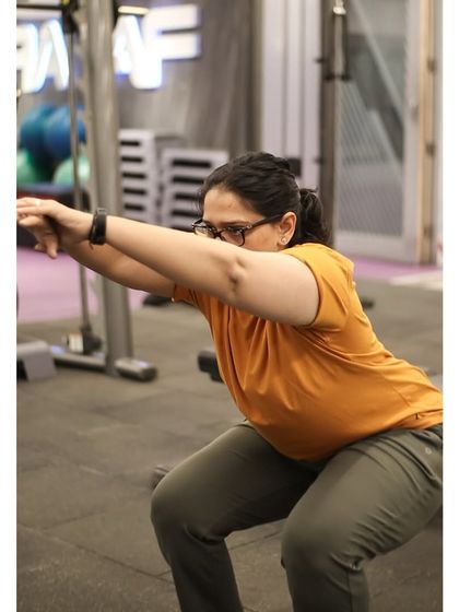 A member holds a deep bodyweight squat, showcasing great mobility and form. This is a foundational movement for overall fitness.