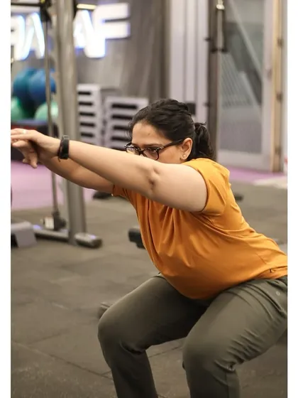 A member holds a deep bodyweight squat, showcasing great mobility and form. This is a foundational movement for overall fitness.