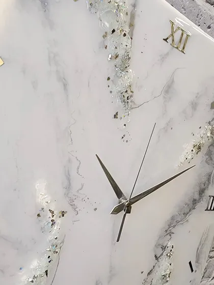 A timeless beauty dispatched to its new home. This 18 by 18 inch square clock features a white marble design with delicate crystal and gold details.