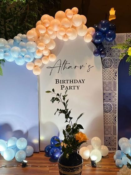 A unique and elegant blue Moroccan theme for a first birthday party. The backdrop features custom arch panels and a beautiful balloon arrangement in shades of blue, white, and peach.