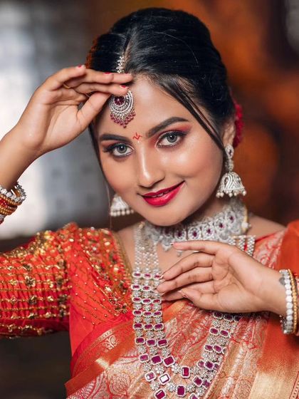 A close-up on the bride's happy face, framed by our beautiful maang tikka and statement earrings from the ruby and diamond-look set.