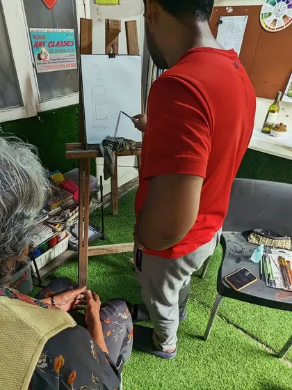 An instructor demonstrating sketching techniques on an easel to an adult student. We provide hands-on guidance to help students master new skills.