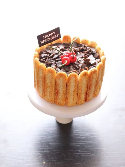 A miniature chocolate truffle cake on a stand, perfect for a tiny birthday celebration.