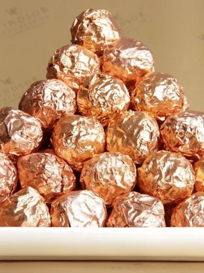 A pyramid of my signature NOCOCHOCO hazelnut truffles, each wrapped in rose gold foil. These are made with fresh toasted hazelnuts, crunchy wafer, and creamy milk chocolate for an irresistible texture.