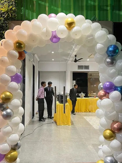 Balloon arches are a great way to welcome guests. This arch, made with white balloons and pops of metallic colors, creates an impressive and festive entrance for any party or event.