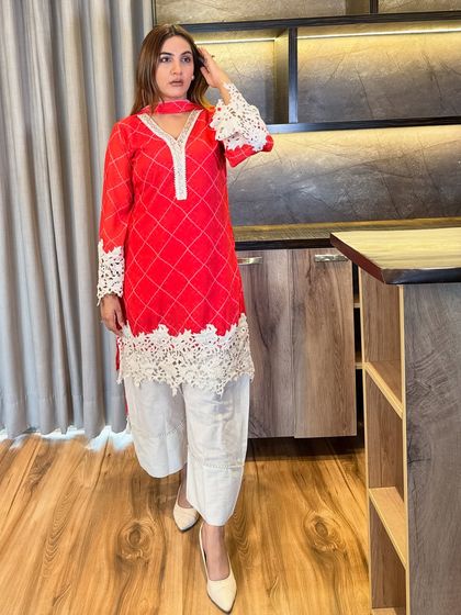 A full-length view of the red kurta set, showing how the neutral cropped pants balance the bold top. The length is universally flattering, and the pointed footwear helps to elongate the legs.