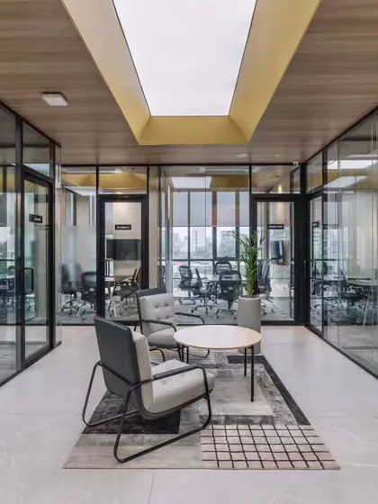 This is a workspace designed for clarity and connection. The design uses glass partitions and open breakout areas to encourage collaboration, while a skylight and neutral tones create a bright, focused atmosphere for the team at RATNAAFIN.