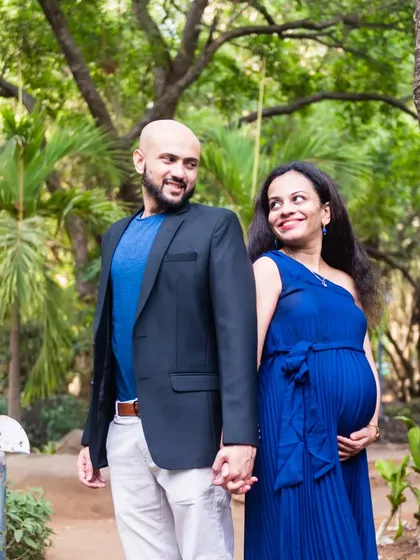 A lovely walking shot of a couple holding hands in the park. The mom-to-be looks elegant in a royal blue dress.